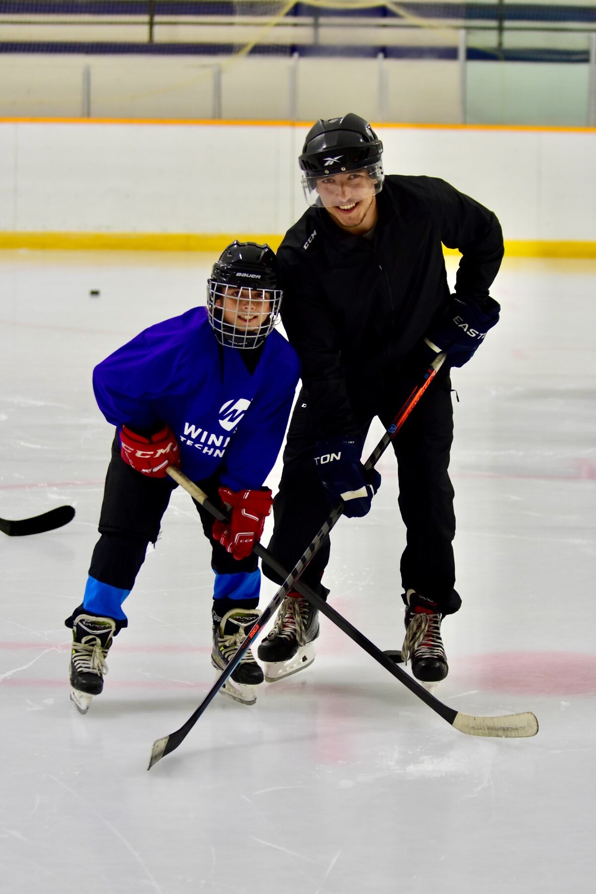 Charles coaching a young hockey player on the ice